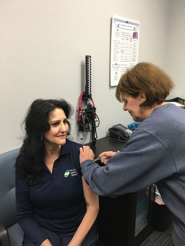 A pharmacist administers a shot to a patient Immunizations